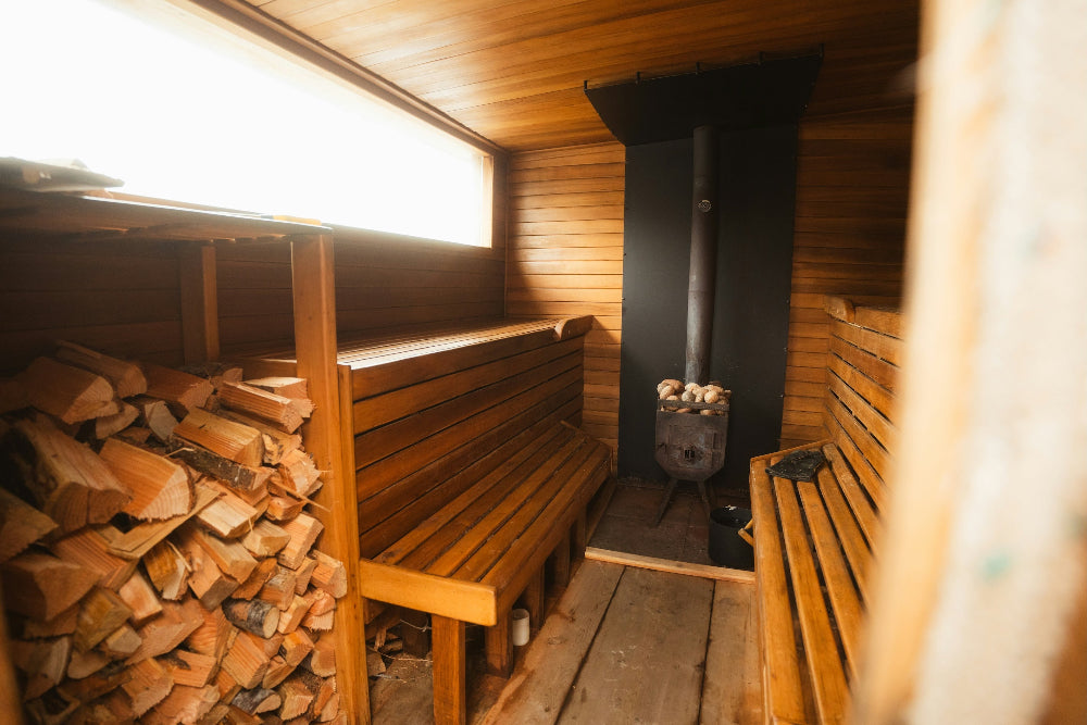 Mobile wooden sauna interior with benches and stacked firewood.