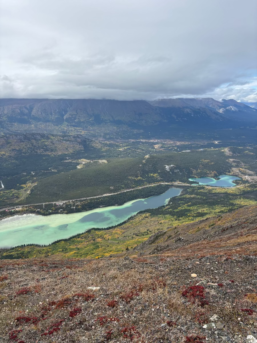 Scenic view of a mountainous landscape with lakes and a cloudy sky.