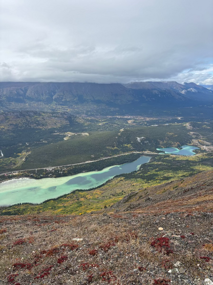 Scenic view of a mountainous landscape with lakes and a cloudy sky.