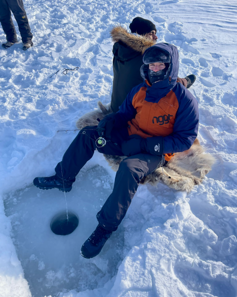 Two people ice fishing on a frozen lake, Inuvik, Canada