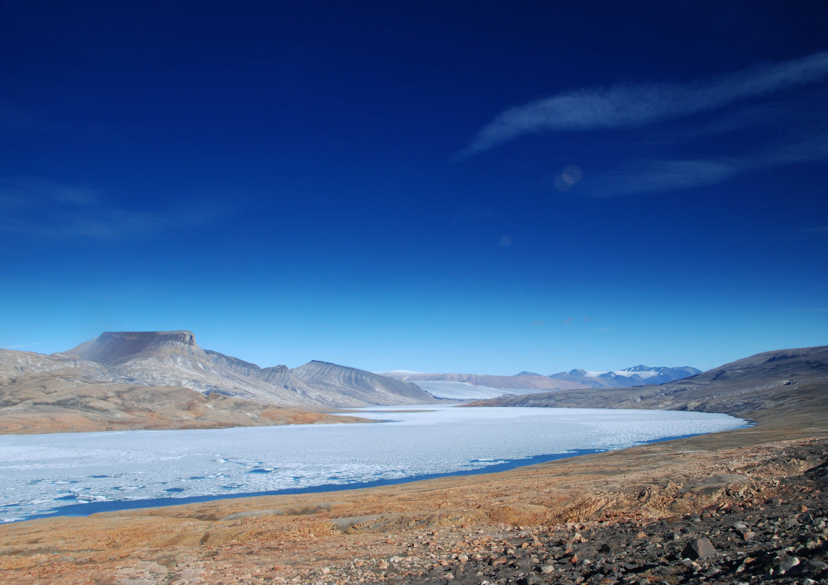 Scenic view of a frozen lake with mountains in the background under a clear blue sky.