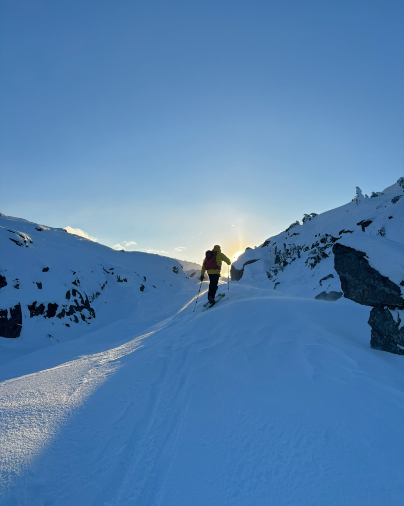 Person backcountry ski, skin up a snowy mountain with a clear blue sky Yukon Canada