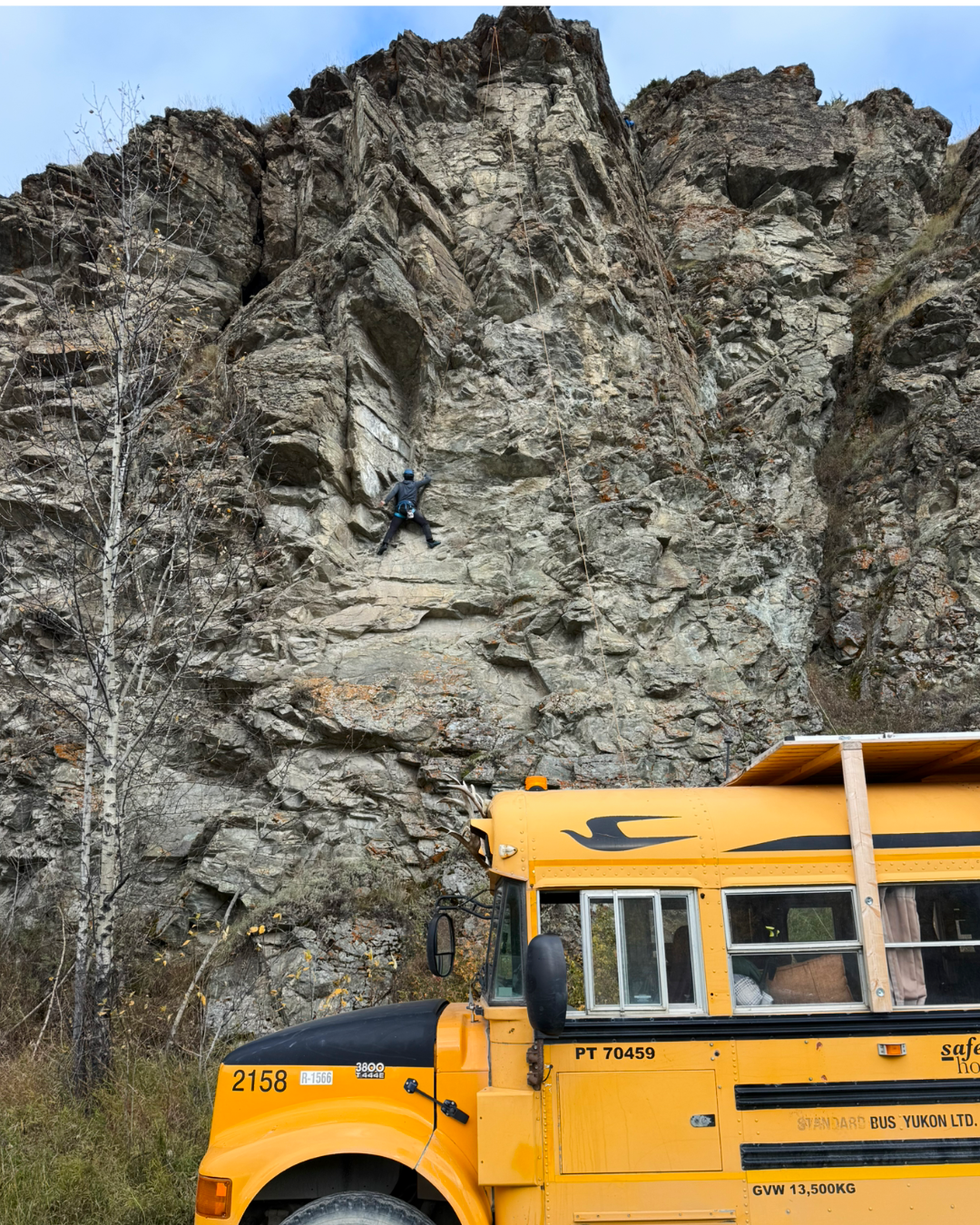 Participant rock climbing with Squatch Bus parked below