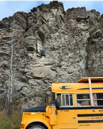 Participant rock climbing with Squatch Bus parked below